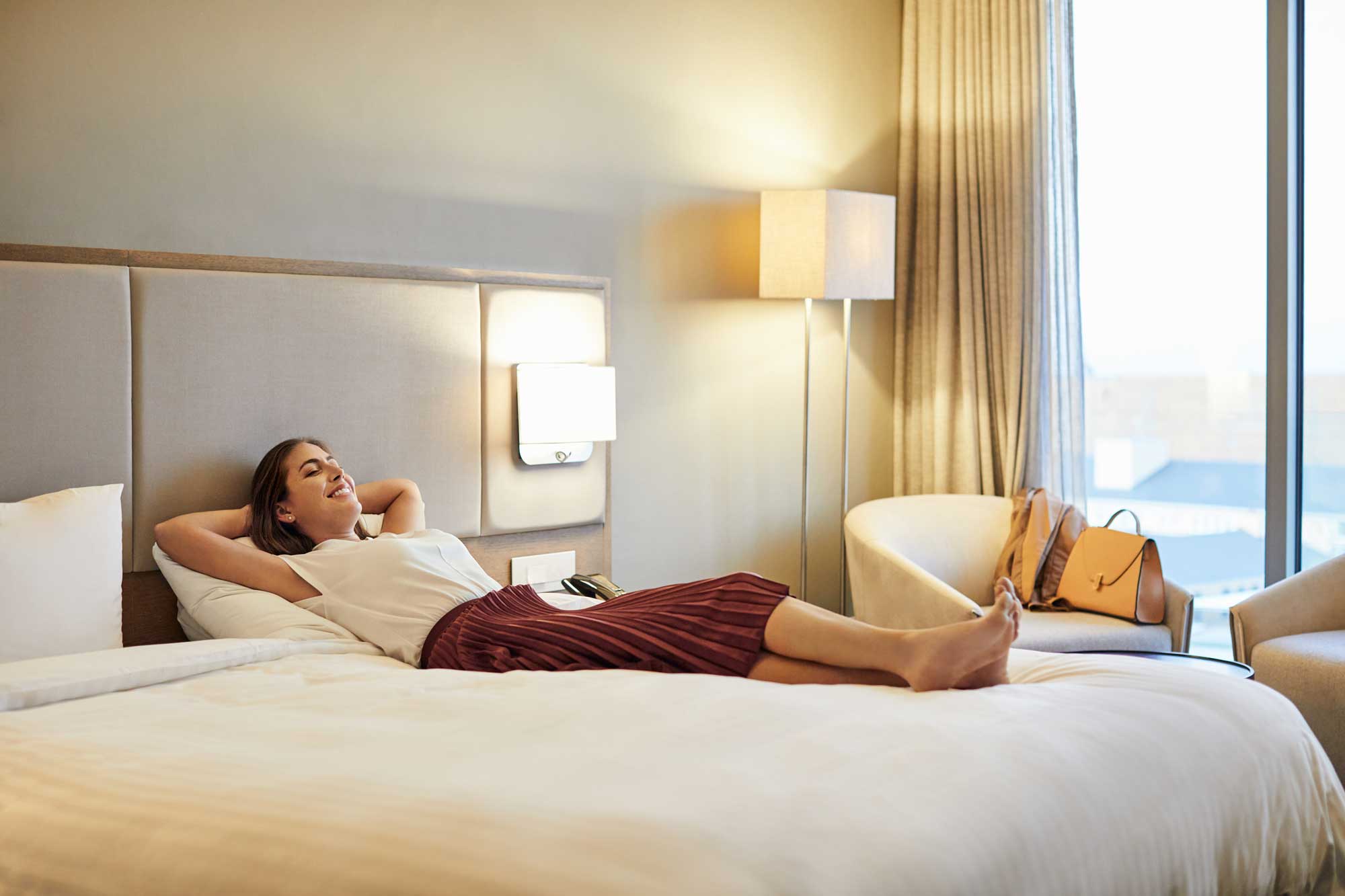 Kvinna som ligger på en säng på ett hotell